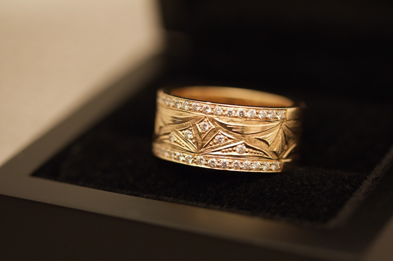 Keltakultainen sormus kuviokaiverruksella ja timanteilla.